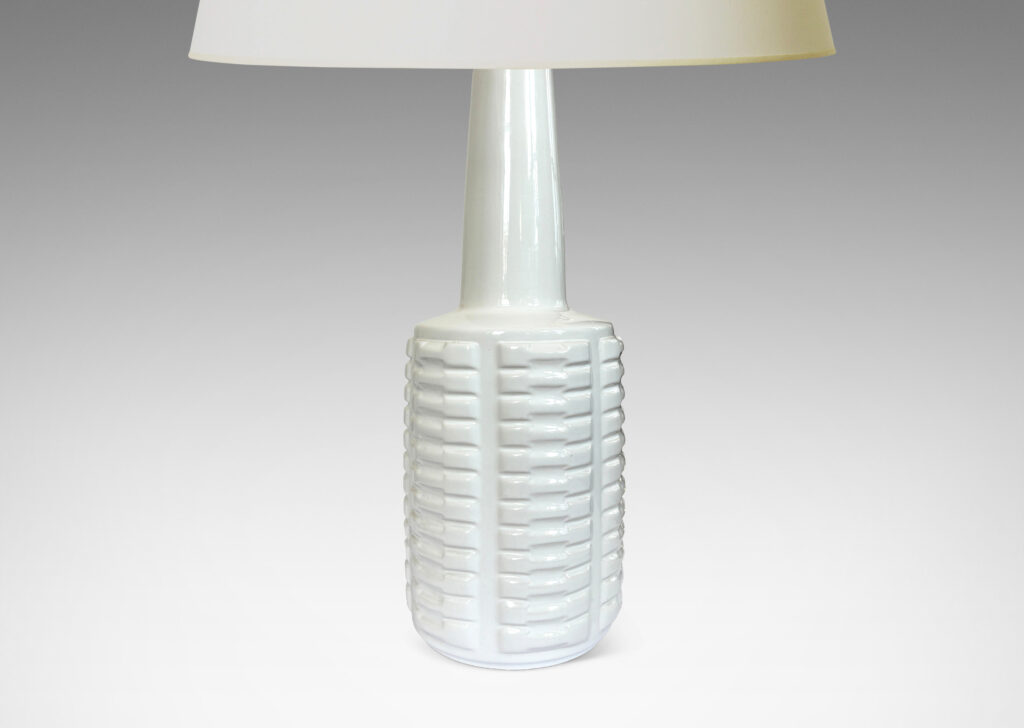 Gallery BAC cylindrical form with stacks of impressed motifs in relief and a tapered neck, glazed in a gloss white