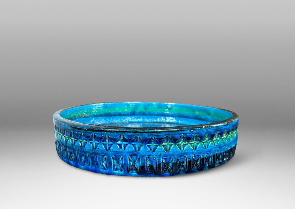 Gallery BAC low straight side and rows of impressed geometric forms, glazed in bright cerulean tones with bands in green-tint and indigo