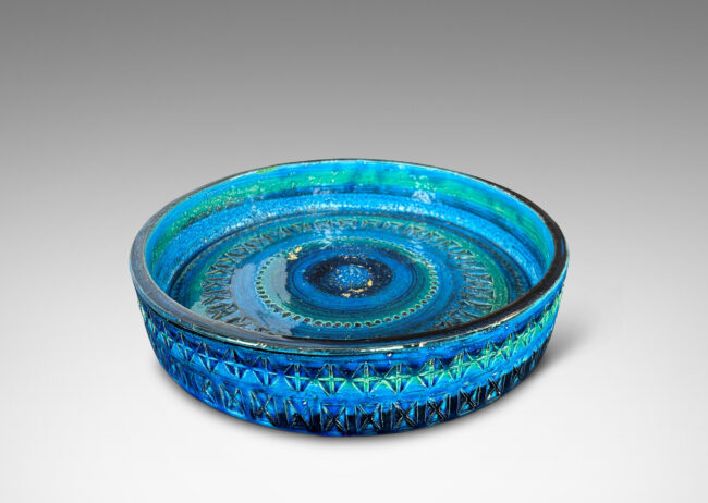 Gallery BAC low straight side and rows of impressed geometric forms, glazed in bright cerulean tones with bands in green-tint and indigo