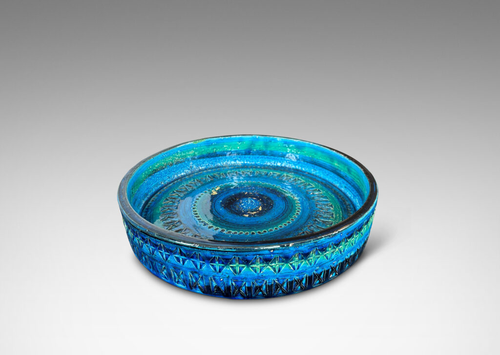 Gallery BAC low straight side and rows of impressed geometric forms, glazed in bright cerulean tones with bands in green-tint and indigo