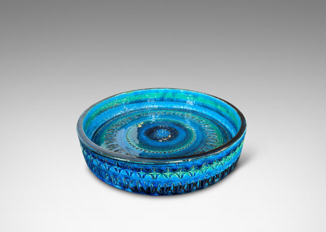 Gallery BAC low straight side and rows of impressed geometric forms, glazed in bright cerulean tones with bands in green-tint and indigo