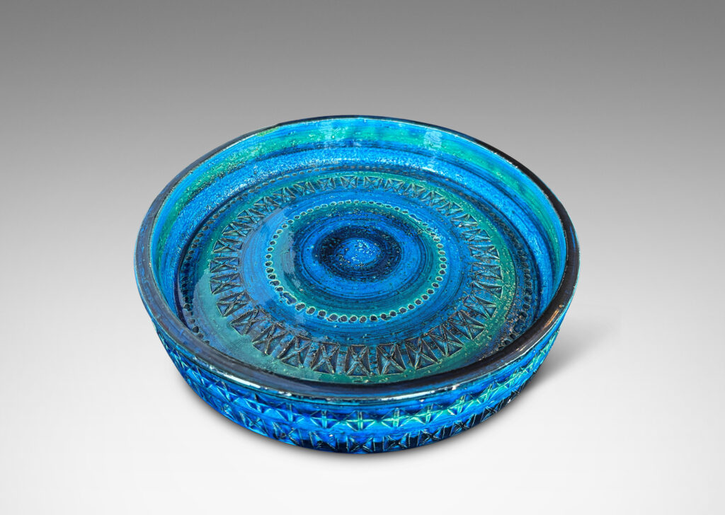 Gallery BAC low straight side and rows of impressed geometric forms, glazed in bright cerulean tones with bands in green-tint and indigo