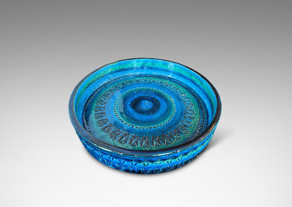 Gallery BAC low straight side and rows of impressed geometric forms, glazed in bright cerulean tones with bands in green-tint and indigo
