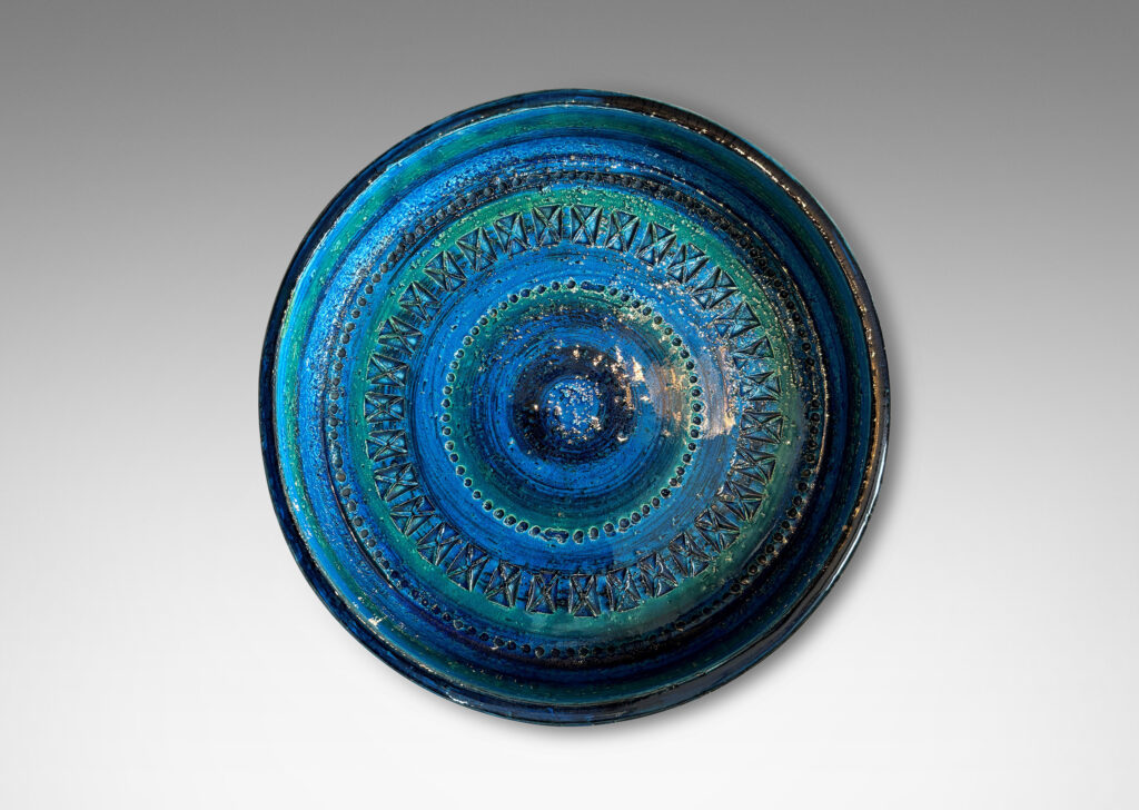 Gallery BAC low straight side and rows of impressed geometric forms, glazed in bright cerulean tones with bands in green-tint and indigo