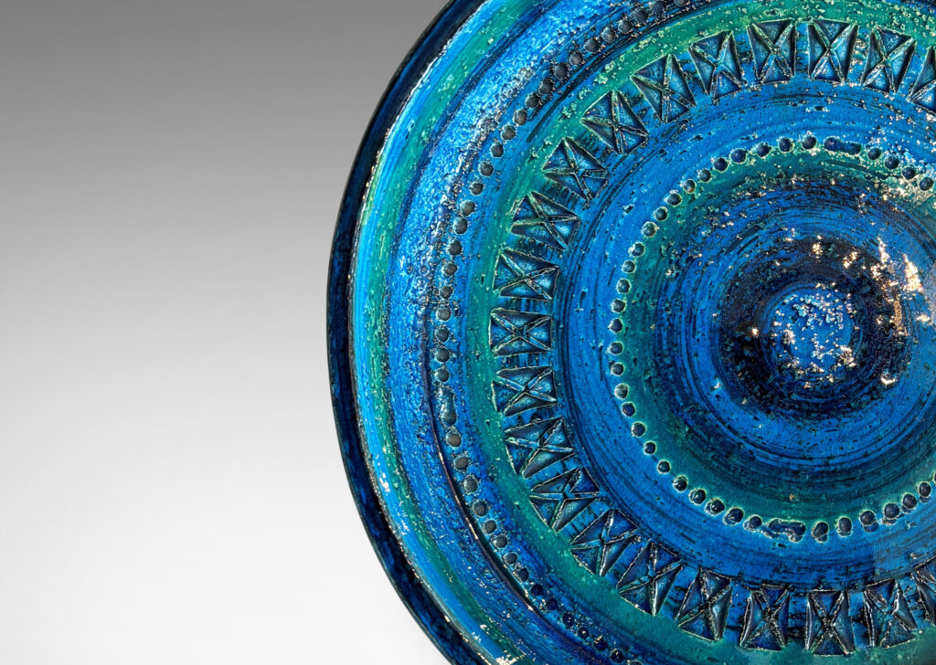 Gallery BAC low straight side and rows of impressed geometric forms, glazed in bright cerulean tones with bands in green-tint and indigo