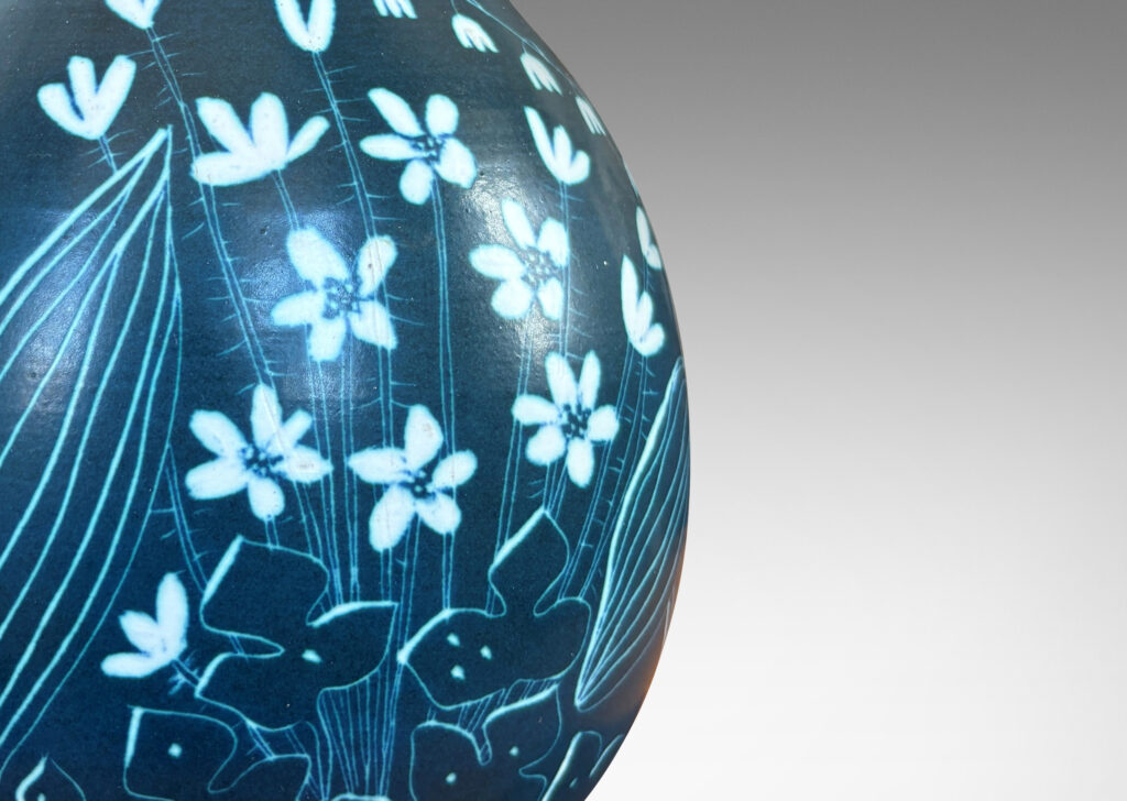 Gallery BAC ovoid form glazed in a deep cerulean tone, with a carved sgraffito wildflower design