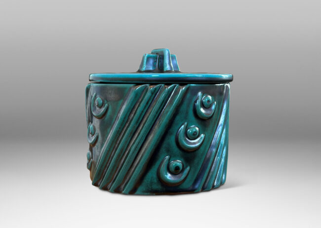 Gallery BAC cylindrical form enlivened with diagonal stripes and motifs in relief, with disk lid top by a cross form final, finished in a tonal teal copper oxide glaze