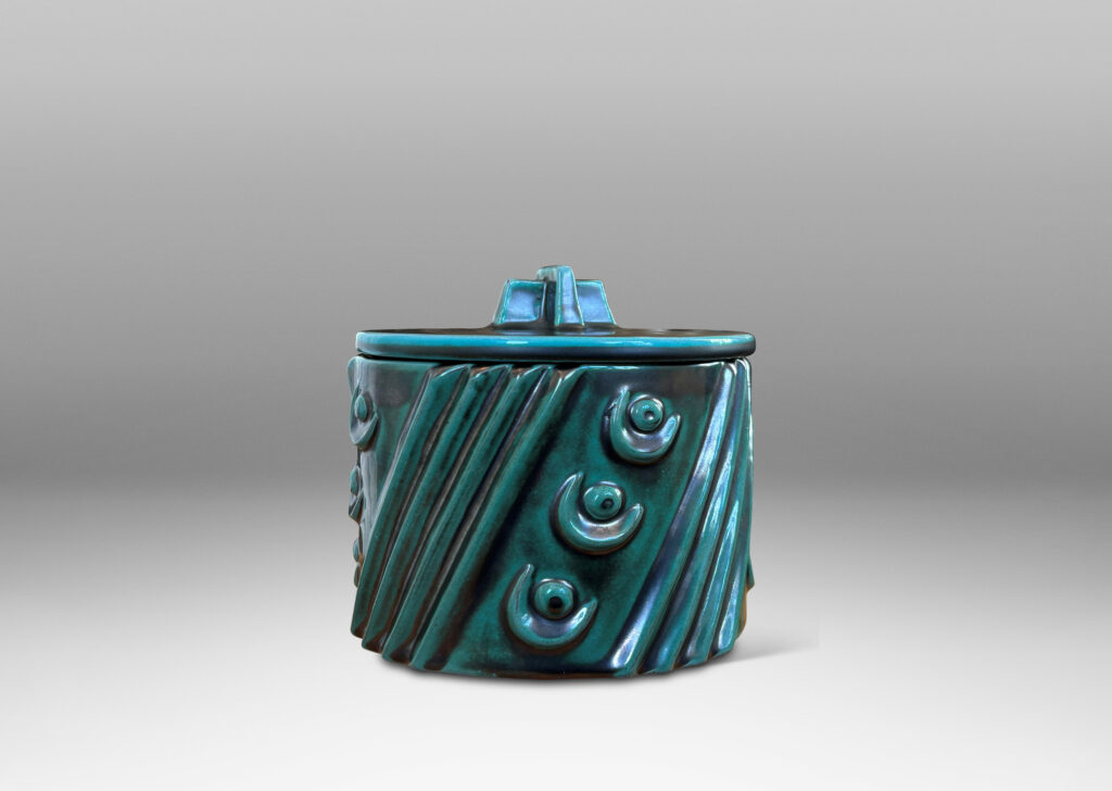 Gallery BAC cylindrical form enlivened with diagonal stripes and motifs in relief, with disk lid top by a cross form final, finished in a tonal teal copper oxide glaze