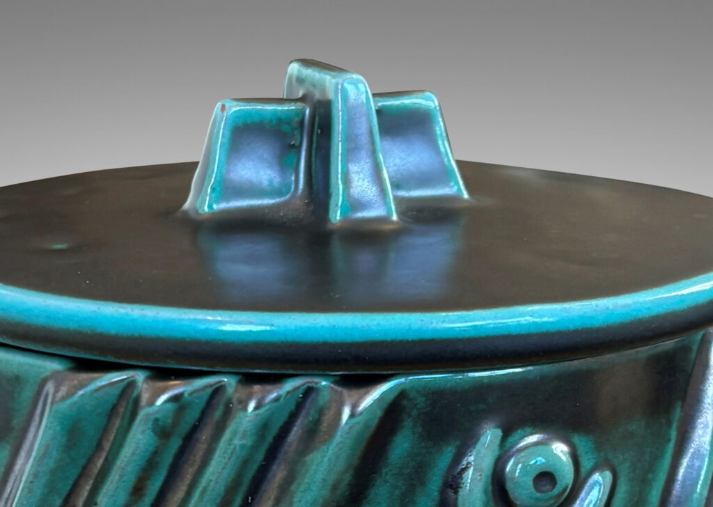Gallery BAC cylindrical form enlivened with diagonal stripes and motifs in relief, with disk lid top by a cross form final, finished in a tonal teal copper oxide glaze