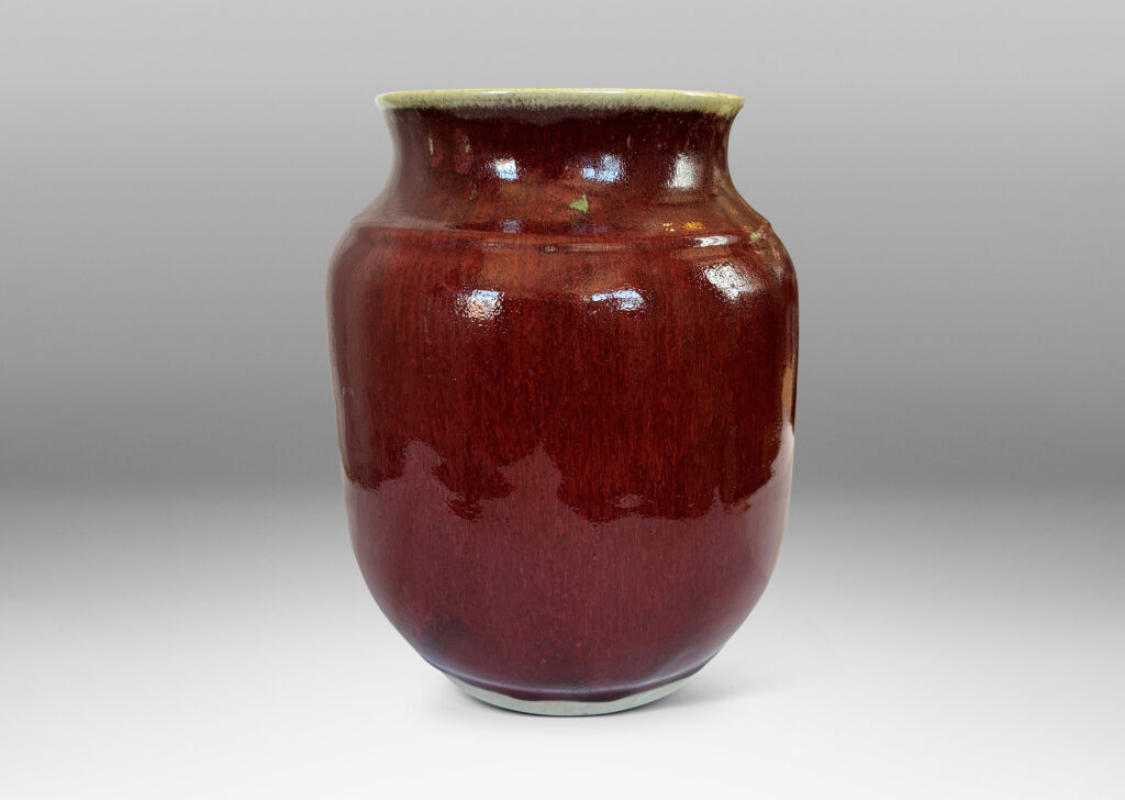 Gallery BAC large tapered cylindrical form with cove neck and wide flared mouth, glazed in a deep burgundy oxblood with pale gray accents