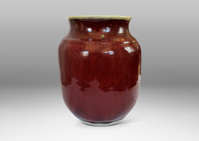 Gallery BAC large tapered cylindrical form with cove neck and wide flared mouth, glazed in a deep burgundy oxblood with pale gray accents
