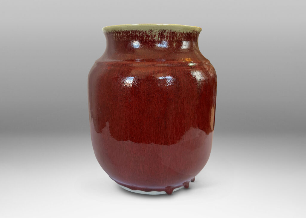Gallery BAC large tapered cylindrical form with cove neck and wide flared mouth, glazed in a deep burgundy oxblood with pale gray accents