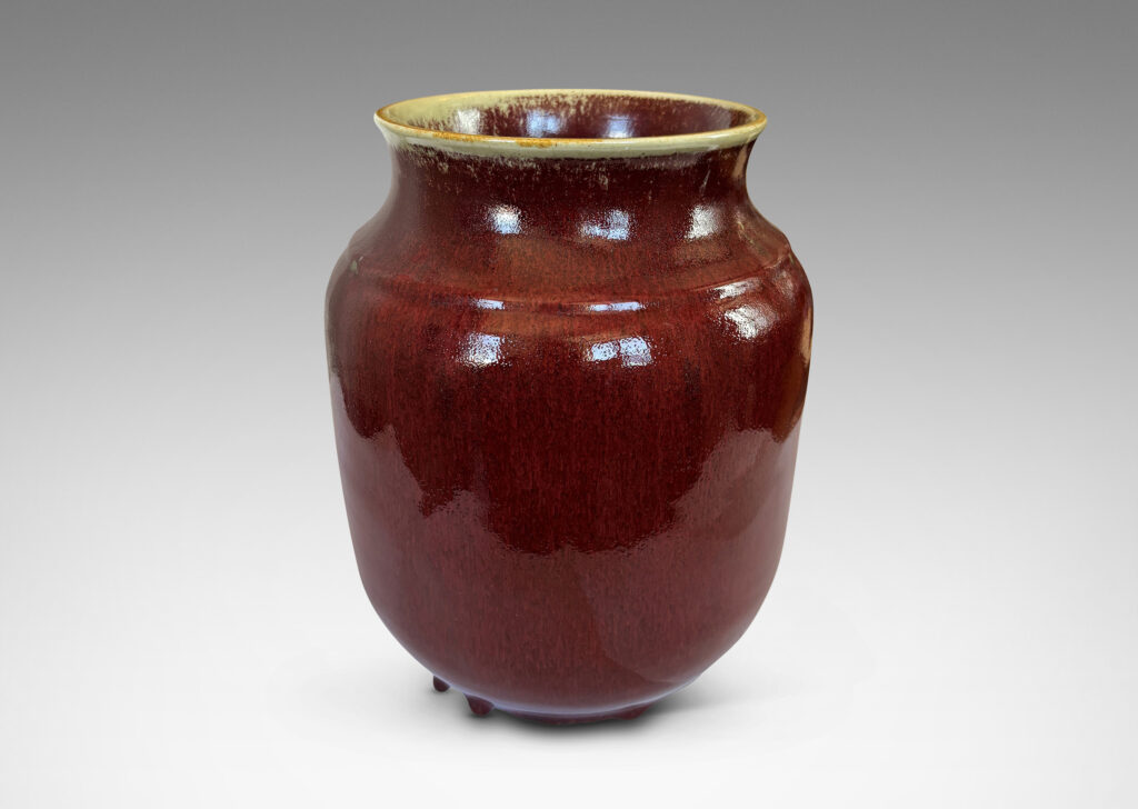 Gallery BAC large tapered cylindrical form with cove neck and wide flared mouth, glazed in a deep burgundy oxblood with pale gray accents
