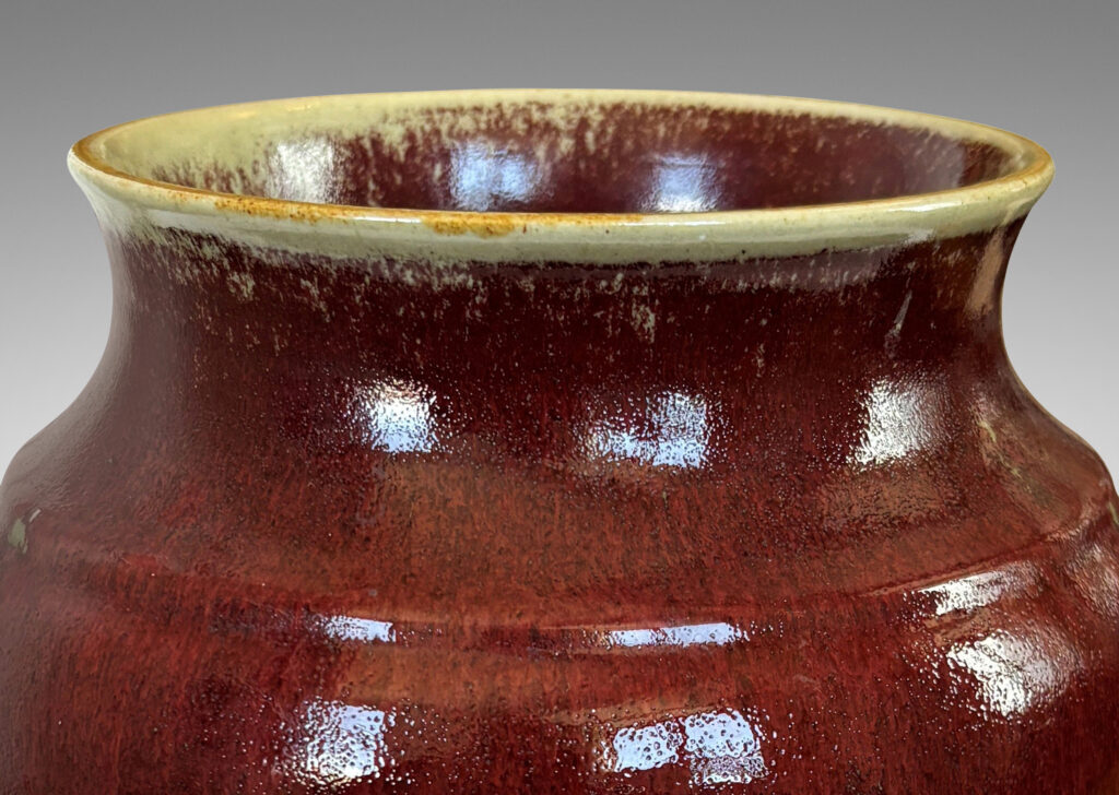 Gallery BAC large tapered cylindrical form with cove neck and wide flared mouth, glazed in a deep burgundy oxblood with pale gray accents