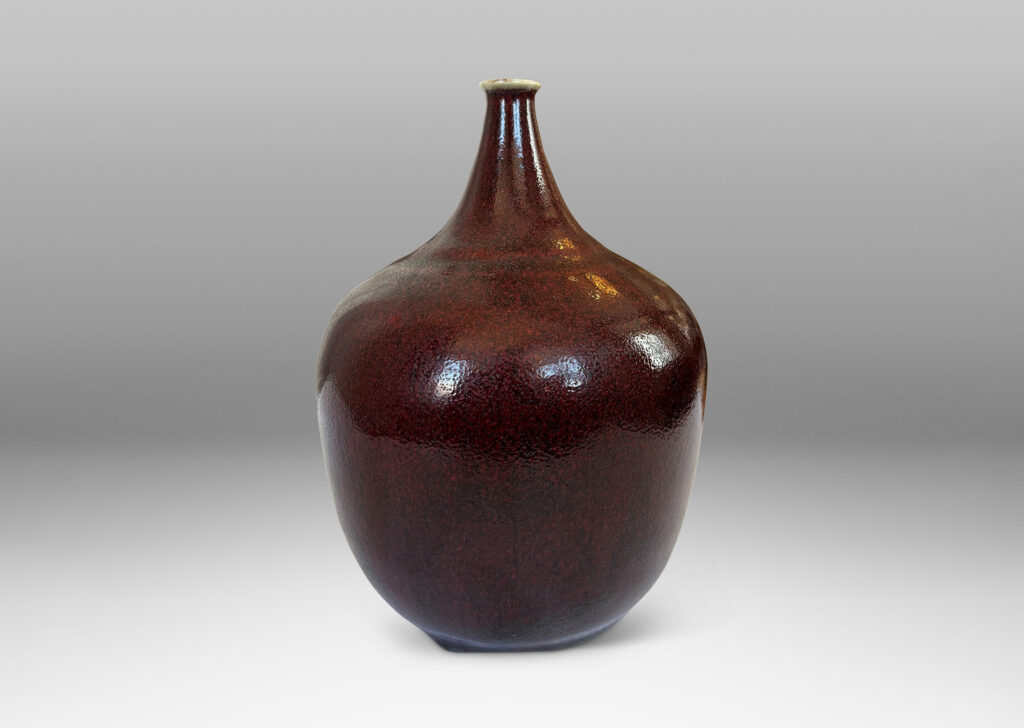 Gallery BAC globe form with straight tapered sides and small sprouted mouth, glazed in a deep burgundy oxblood with pale gray accents