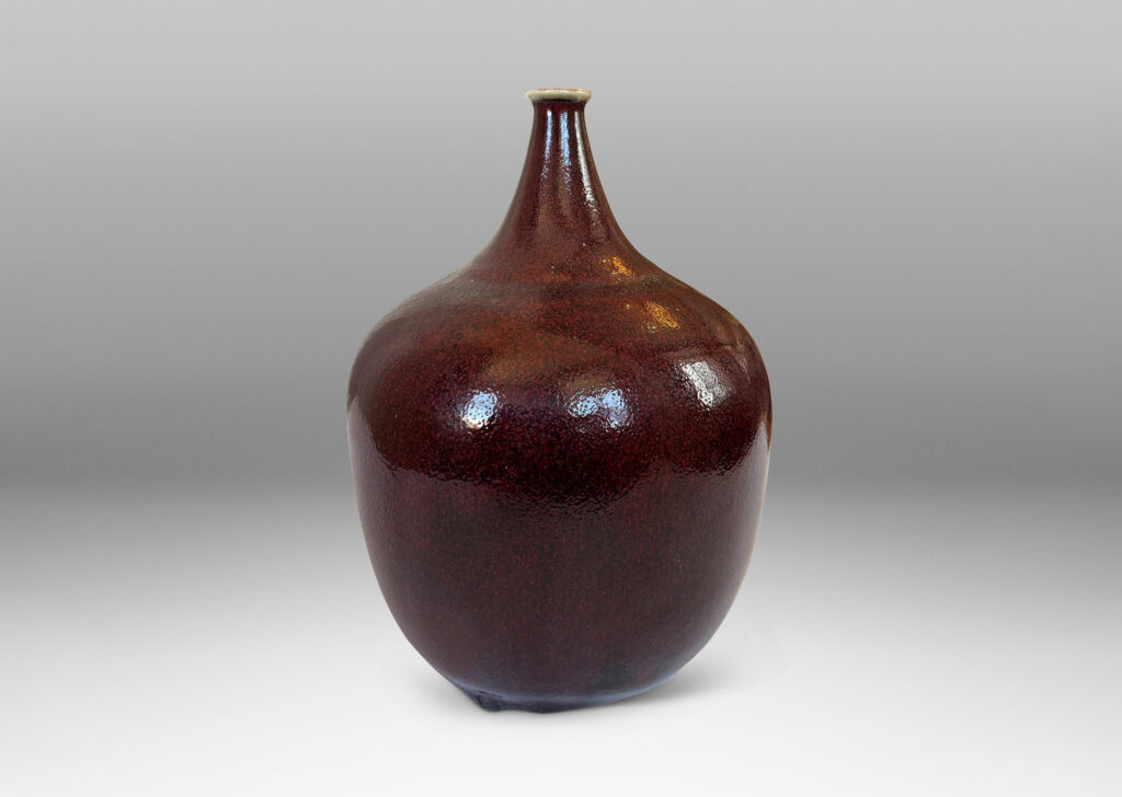 Gallery BAC globe form with straight tapered sides and small sprouted mouth, glazed in a deep burgundy oxblood with pale gray accents