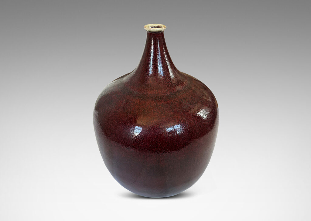 Gallery BAC globe form with straight tapered sides and small sprouted mouth, glazed in a deep burgundy oxblood with pale gray accents