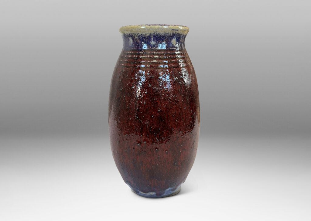 Gallery BAC ovoid form with wide outstretched mouth and ridged shoulder, glazed in a deep burgundy oxblood with pale gray accents