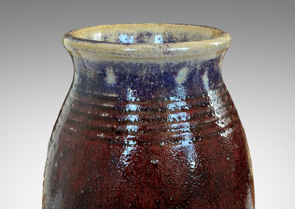 Gallery BAC ovoid form with wide outstretched mouth and ridged shoulder, glazed in a deep burgundy oxblood with pale gray accents