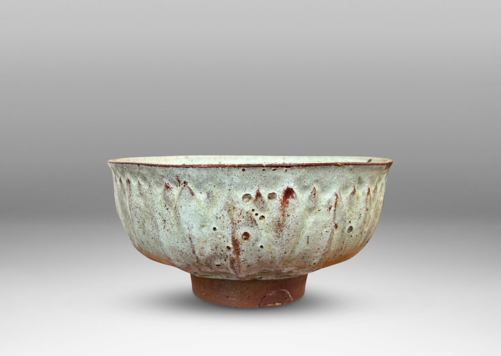 Gallery BAC round form with gently flared lip, on a high reveal, encircled in a relief pattern of overlapping leaves, glazed in a celadon tinted white