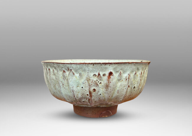 Gallery BAC round form with gently flared lip, on a high reveal, encircled in a relief pattern of overlapping leaves, glazed in a celadon tinted white