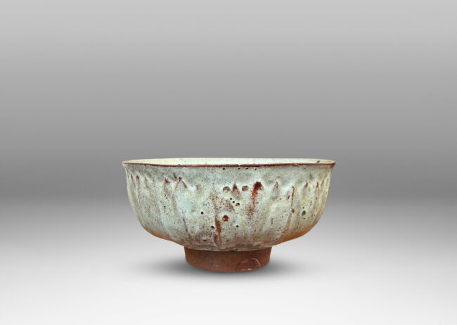 Gallery BAC round form with gently flared lip, on a high reveal, encircled in a relief pattern of overlapping leaves, glazed in a celadon tinted white