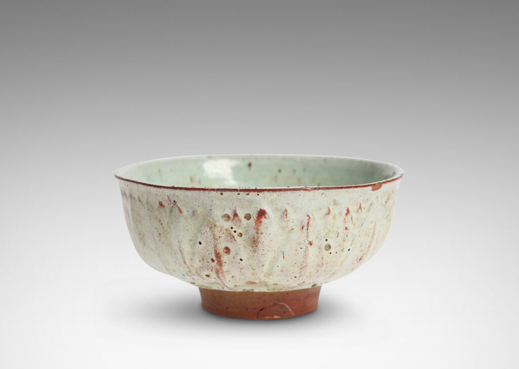 Gallery BAC round form with gently flared lip, on a high reveal, encircled in a relief pattern of overlapping leaves, glazed in a celadon tinted white