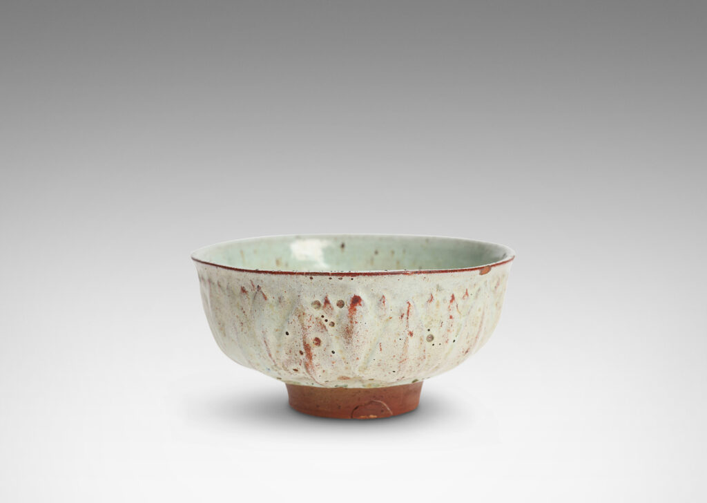 Gallery BAC round form with gently flared lip, on a high reveal, encircled in a relief pattern of overlapping leaves, glazed in a celadon tinted white