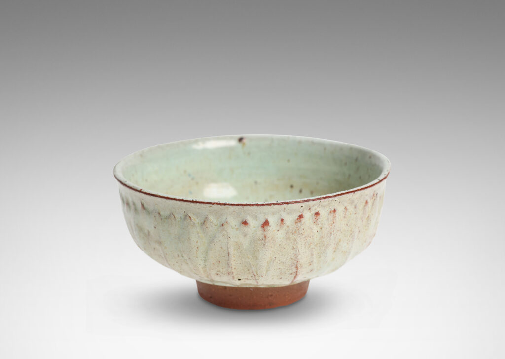 Gallery BAC round form with gently flared lip, on a high reveal, encircled in a relief pattern of overlapping leaves, glazed in a celadon tinted white