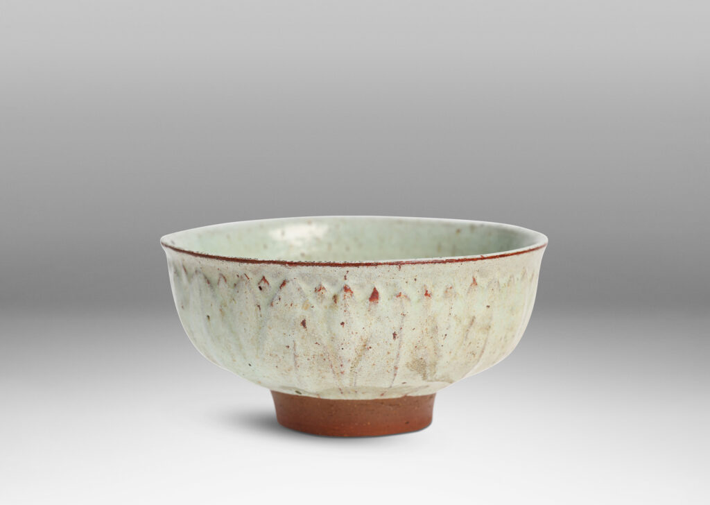 Gallery BAC round form with gently flared lip, on a high reveal, encircled in a relief pattern of overlapping leaves, glazed in a celadon tinted white