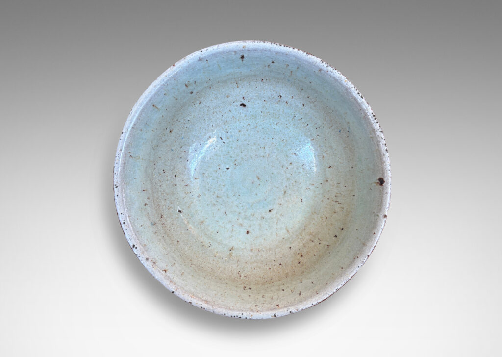 Gallery BAC round form with gently flared lip, on a high reveal, encircled in a relief pattern of overlapping leaves, glazed in a celadon tinted white
