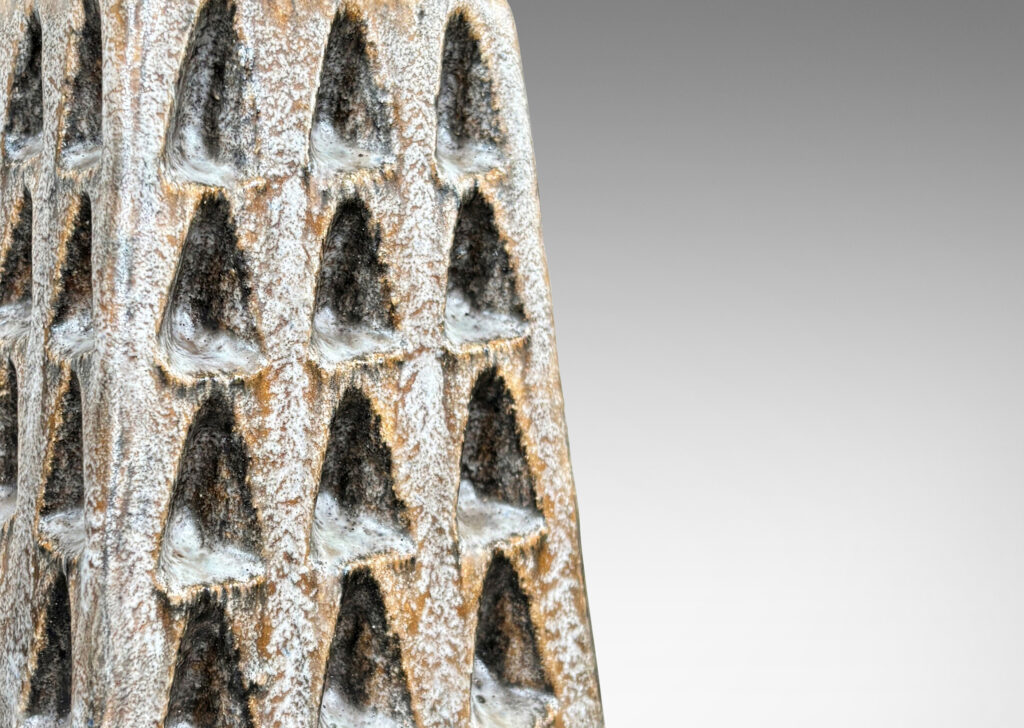 Gallery BAC square tapered obelisk-like forms with carved patterns of triangle motifs, glazed in running pale gray and matte brown