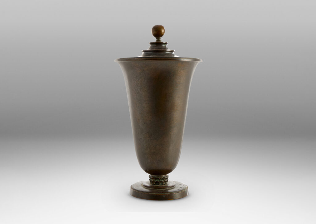 Gallery BAC sinuously modeled “U” form on a stepped disk plinth, with tiered lid topped with a sphere finial; patinate bronze
