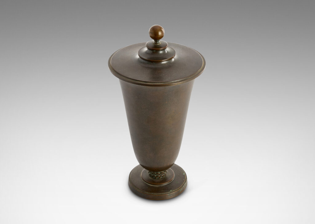 Gallery BAC sinuously modeled “U” form on a stepped disk plinth, with tiered lid topped with a sphere finial; patinate bronze