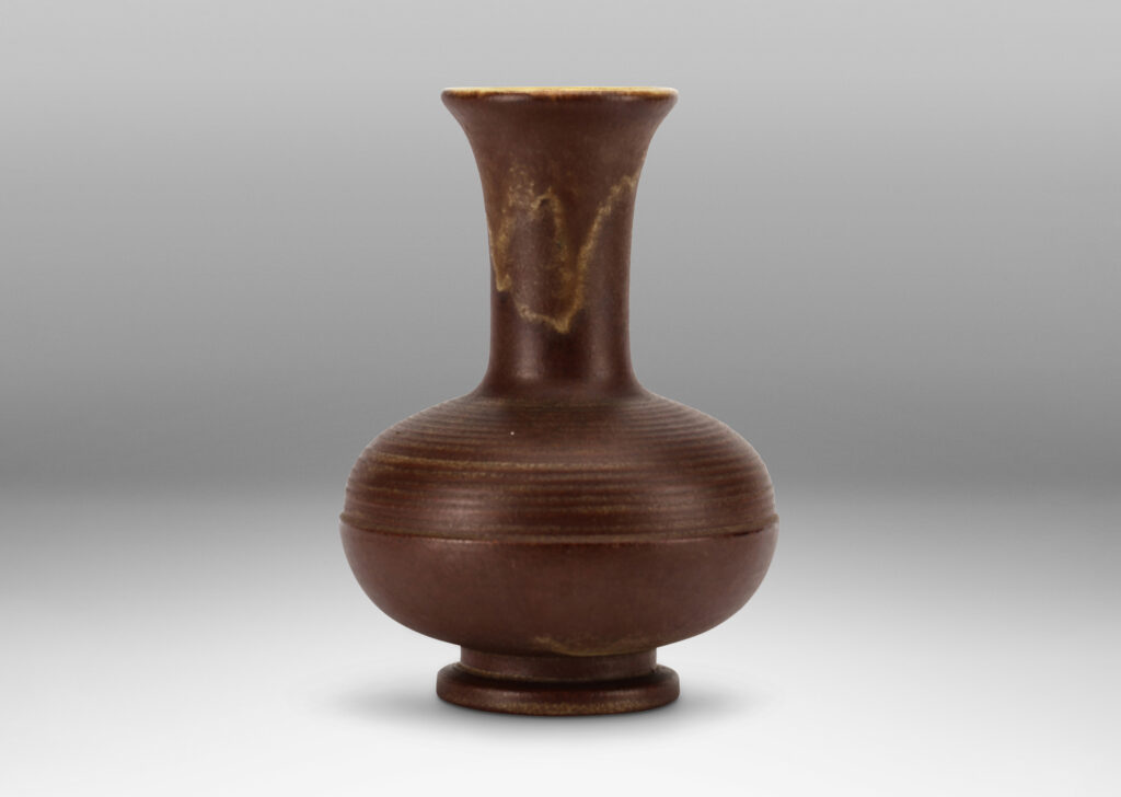Gallery BAC decanter-like form, with ridged compressed globe body and tall neck with flared mouth, glazed in matte brown with butter yellow interior