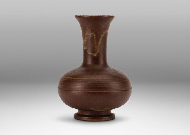 Gallery BAC decanter-like form, with ridged compressed globe body and tall neck with flared mouth, glazed in matte brown with butter yellow interior