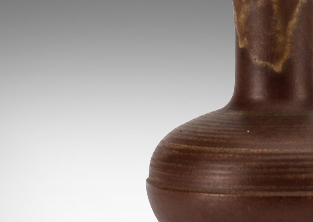Gallery BAC decanter-like form, with ridged compressed globe body and tall neck with flared mouth, glazed in matte brown with butter yellow interior