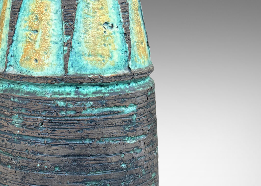 Gallery BAC cylindrical form with its top half upwardly tapered, with carved triangular motifs, glazed in matte brown with green and mustard yellow