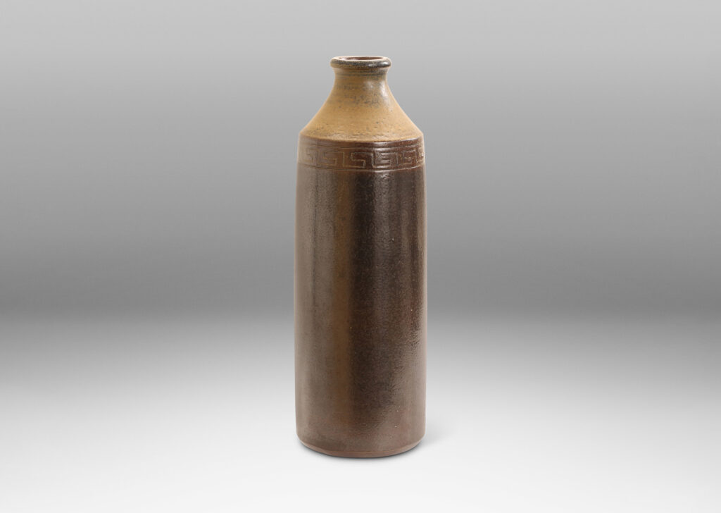 Gallery BAC large bottle form with columnar form, coved neck and carved Greek key band, glazed in light and dark brown