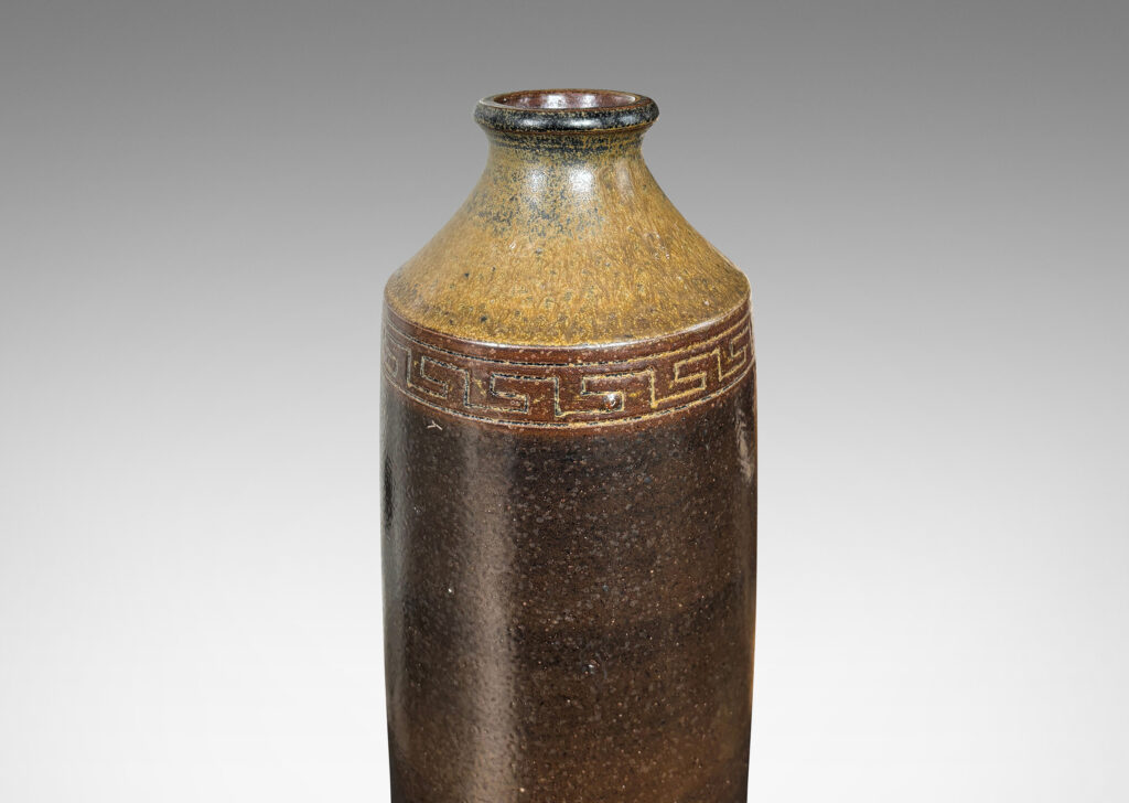 Gallery BAC large bottle form with columnar form, coved neck and carved Greek key band, glazed in light and dark brown