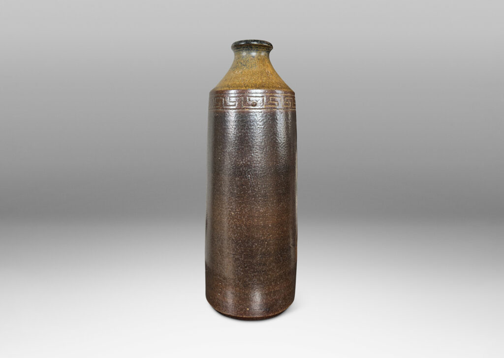 Gallery BAC large bottle form with columnar form, coved neck and carved Greek key band, glazed in light and dark brown