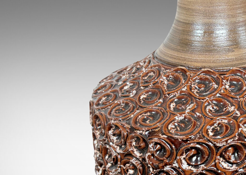 Gallery BAC floating drum form ornamented with swirl motifs glazed in a ganache brown, with sprouting neck and foot glazed in a striae gray-brown