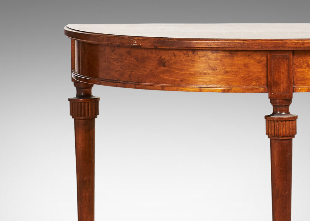 Gallery BAC semi-circular top with checkerboard marquetry and three round tapered legs with stylized tassel headers, which together form a circular table