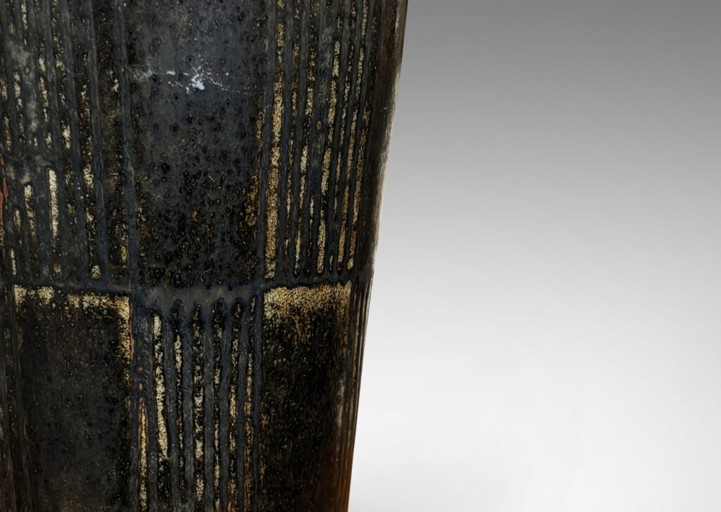 Gallery BAC wide tapered cylindrical form with alternating panels of carved verticals, glazed in brown-black with red luster
