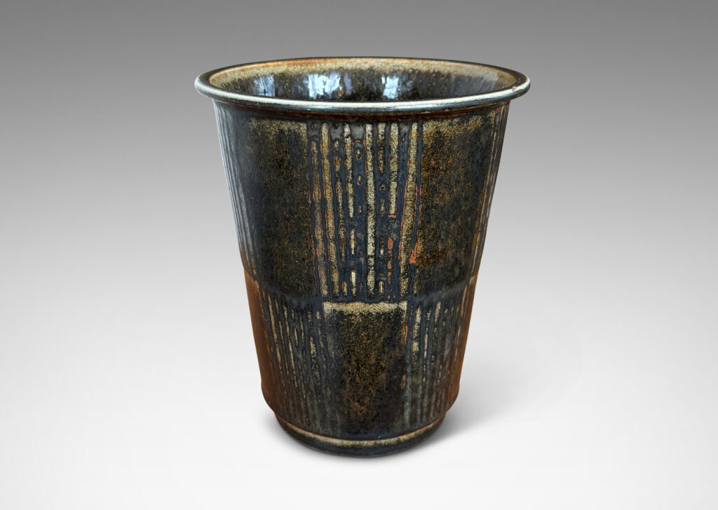 Gallery BAC wide tapered cylindrical form with alternating panels of carved verticals, glazed in brown-black with red luster