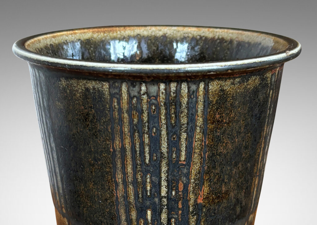 Gallery BAC wide tapered cylindrical form with alternating panels of carved verticals, glazed in brown-black with red luster
