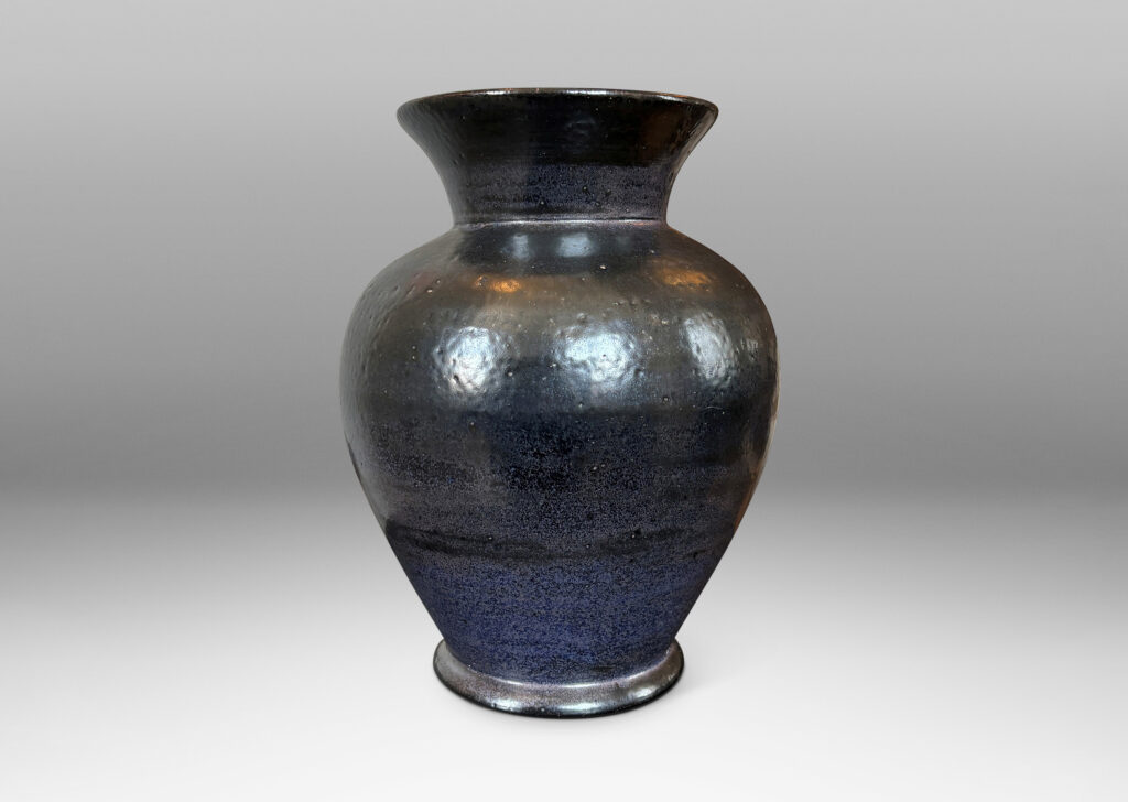 Gallery BAC tapered form with flared mouth, glazed in black with hints of purple with an orange peel texture