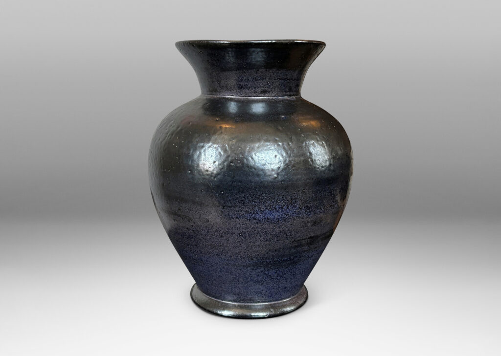 Gallery BAC tapered form with flared mouth, glazed in black with hints of purple with an orange peel texture