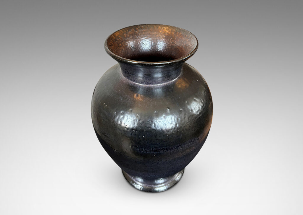 Gallery BAC tapered form with flared mouth, glazed in black with hints of purple with an orange peel texture