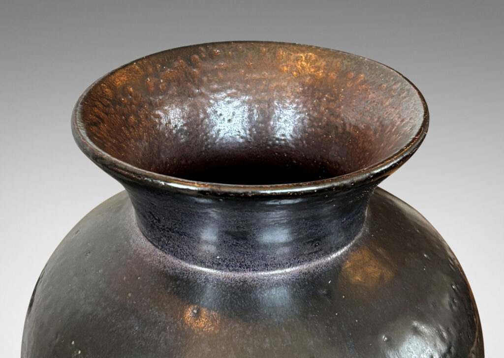 Gallery BAC tapered form with flared mouth, glazed in black with hints of purple with an orange peel texture